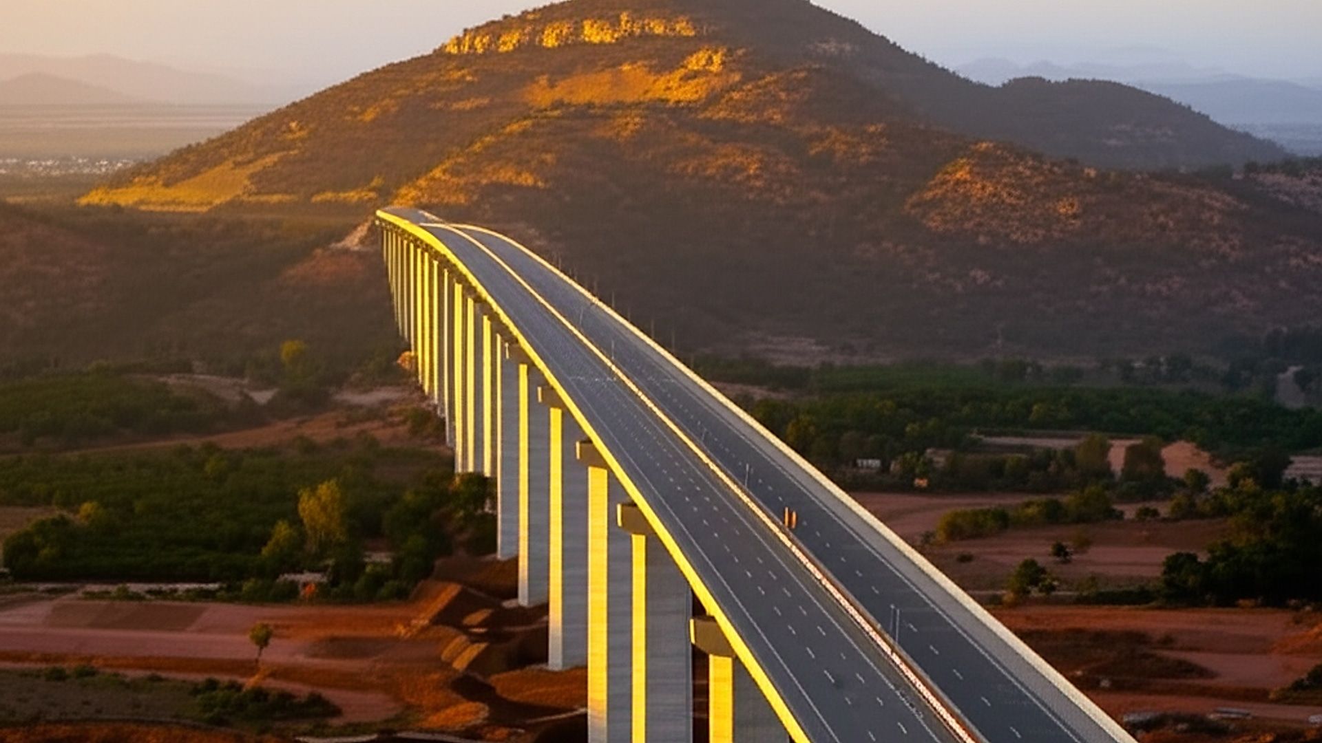 Architectural photograph showcasing a newly completed section of the expressway between Madanapalle and Tirupati, Andhra Pradesh. Focus on an elevated highway section with balanced concrete pillars receding into the distance. Rolling hills and distant, sun-drenched landscapes form the backdrop. Golden hour lighting, just after sunrise, casts long, soft shadows emphasizing the scale and clean lines of the structure. Professional architectural photography style: wide-angle lens, sharp focus, minimal distortion, emphasizing depth of field and the infrastructure’s integration with the natural environment. High resolution, detailed textures.. Professional architectural photography, ultra-high quality, sharp focus, vivid colors, dramatic lighting, golden hour, cinematic composition, 8K UHD, photorealistic.