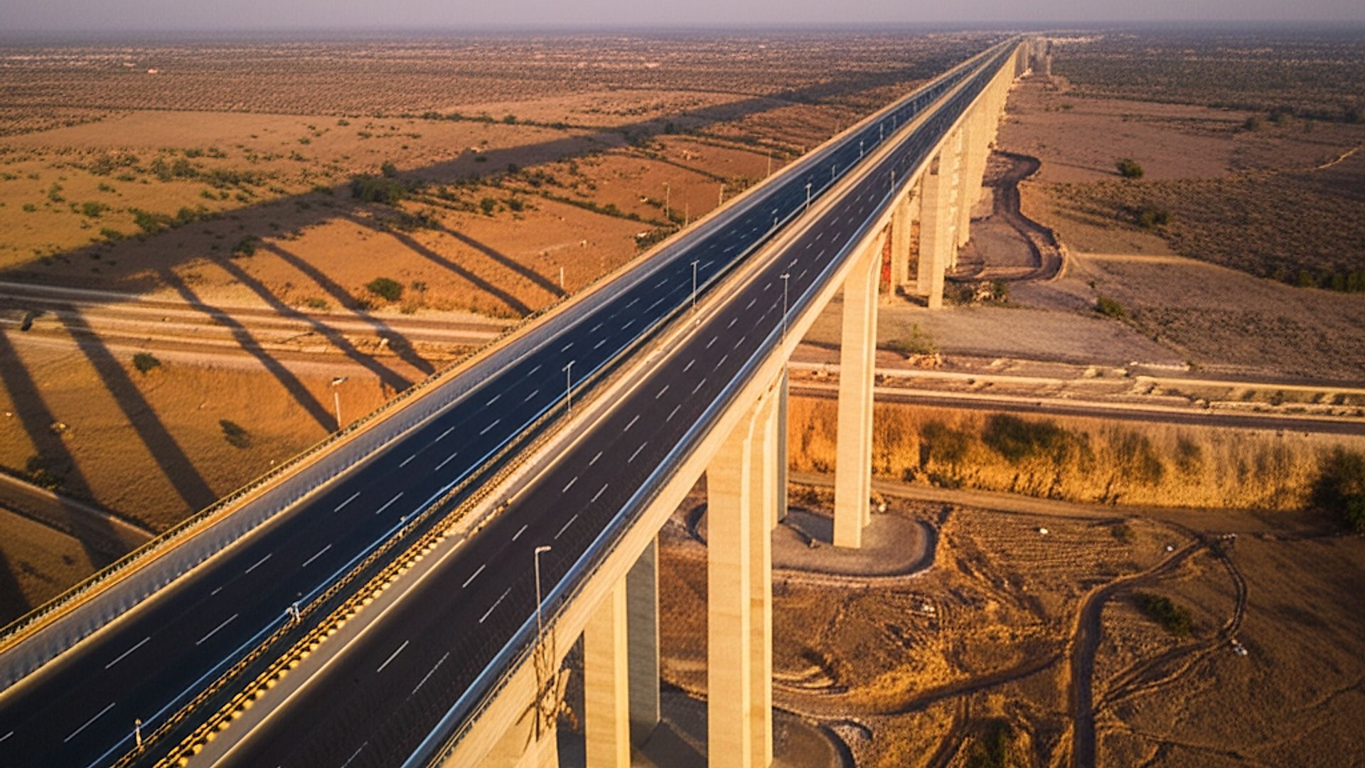 Architectural photograph showcasing the completed NH-148N eight-lane access-controlled expressway bridge. The setting is near Kota, India, with a characteristic arid landscape visible in the background. Capture the scene during golden hour, with warm, diffused sunlight illuminating the bridge structure and casting long shadows. Use a wide-angle lens to emphasize the scale and design. Focus on clean lines, geometric patterns, and the integration of the bridge with its environment. Professional, high-resolution, detailed, and portfolio-worthy quality.. Professional architectural photography, ultra-high quality, sharp focus, vivid colors, dramatic lighting, golden hour, cinematic composition, 8K UHD, photorealistic.
